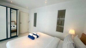 Ett modernt hotellrum med en stor säng, en garderob, en spegel och ett fönster.