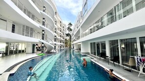 En modern inomhuspool med flera våningsplan av balkonger, glasräcken och fri utsikt mot himlen.