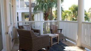 A covered porch with wicker furniture, a small table, and a bench. - Beautiful 4-br 3 king beds, 20 seconds to beach, community pool (Destin)