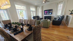 A dining area with a wooden table set for six, surrounded by wicker chairs. - Beautiful 4-br 3 king beds, 20 seconds to beach, community pool (Destin)