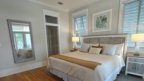 A bedroom with a large bed, a nightstand, a mirror, and a window with blinds. - Beautiful 4-br 3 king beds, 20 seconds to beach, community pool (Destin)