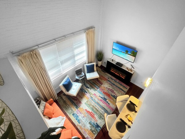 Una sala de estar moderna con chimenea, televisor de pantalla plana y una alfombra colorida.