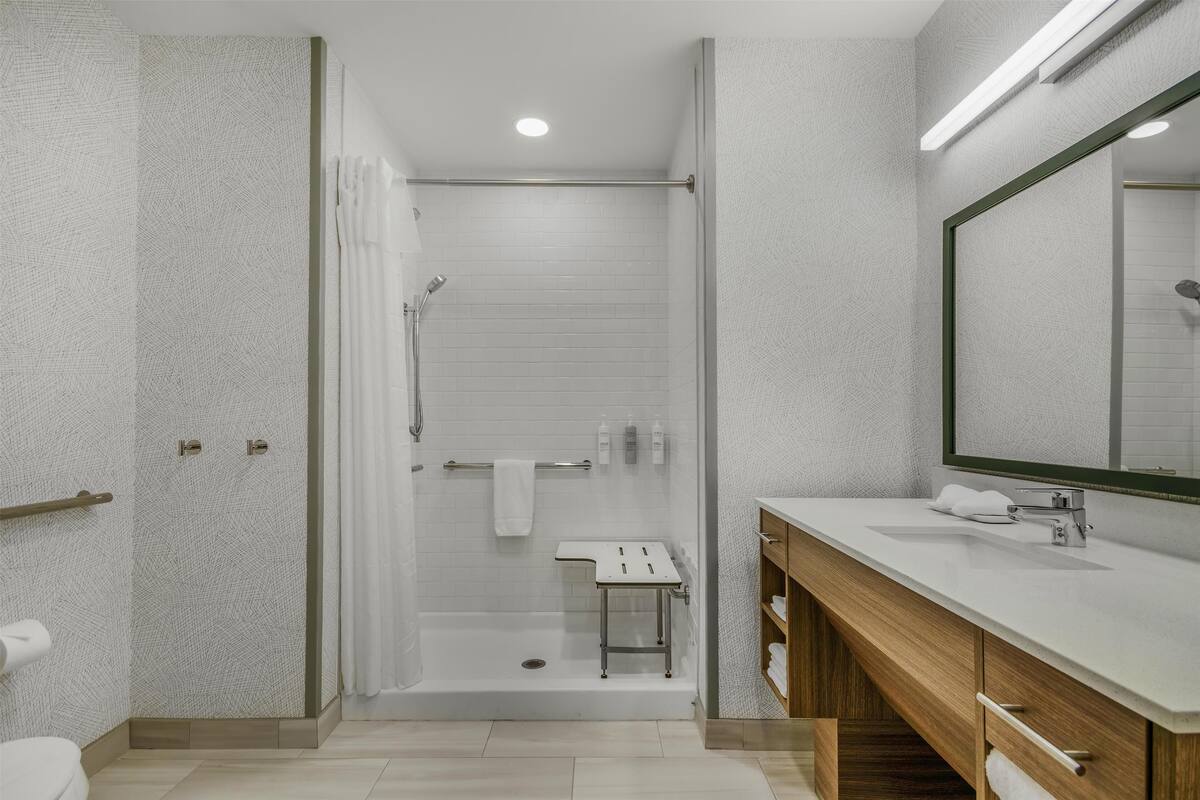 Een moderne badkamer met douche, toilet en wastafel.