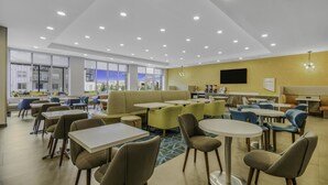 Un comedor moderno con diversas opciones de asientos, incluyendo mesas, sillas, un sofá y una barra con una exhibición de menú.