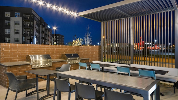 Un patio al aire libre con una parrilla, asientos e iluminación con luces colgantes.
