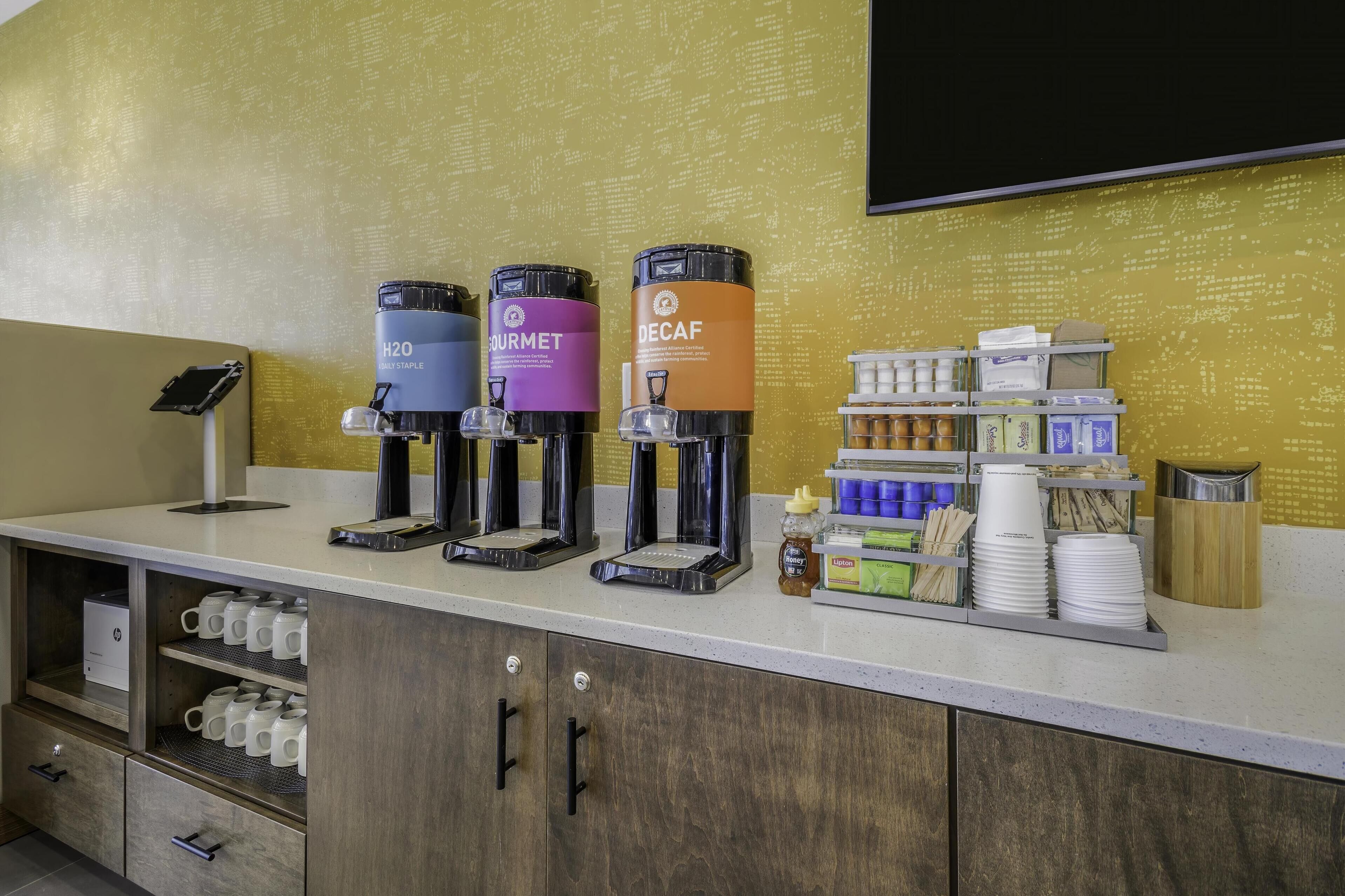 En kaffestation med tre dispensere mærket H2O, AIRMET og DECAF.