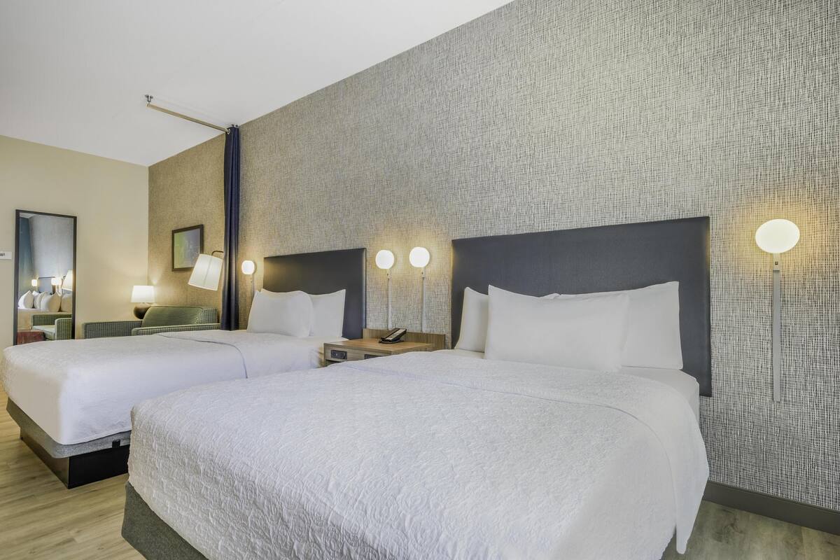 Een hotelkamer met twee bedden, een grote spiegel en wandlampen.