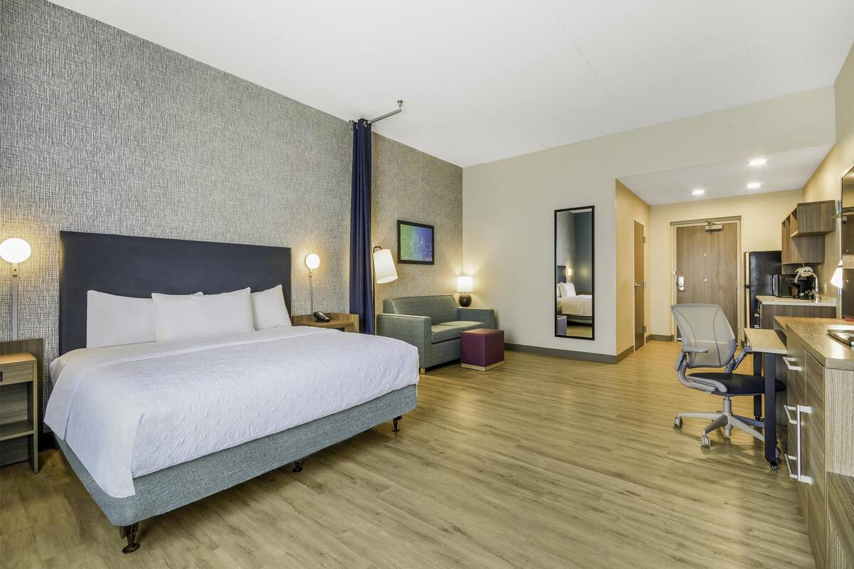 Een moderne hotelkamer met een groot bed, een bureau, een stoel en een zithoekje.