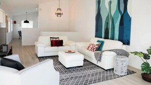 Ein modernes Wohnzimmer mit einem weißen Sofa, einem Couchtisch und einem großen, abstrakten Gemälde an der Wand.