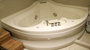 A corner bathtub with a wooden step leading up to it. - Hotel Cancalli Tlaxcala (Tlaxcala)