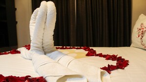 A neatly made bed with a towel arrangement and rose petals. - Hotel Cancalli Tlaxcala (Tlaxcala)