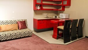 A compact living space with a kitchenette, a patterned sofa, and a dining area with chairs. - Hotel Cancalli Tlaxcala (Tlaxcala)
