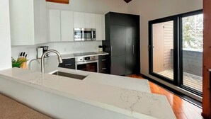 Una cocina moderna con armarios blancos, encimera de mármol y un amplio ventanal con vistas al exterior.