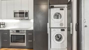A compact kitchen with a Bosch microwave, oven, and stacked washing machines.