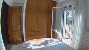 Un dormitorio con cama, armario de madera y puerta corrediza de vidrio a un balcón.
