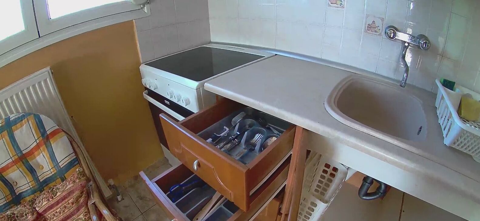 A compact kitchen with a stove, sink, and storage drawers.