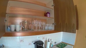Una cocina con estantes de madera, una cafetera y un lavabo.