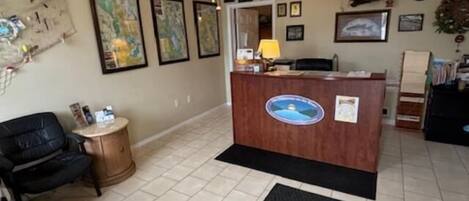A reception area with a wooden desk, black office chair, and a black mat on the floor.