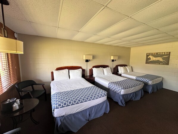A hotel room with three beds, a small table, and a chair. - Grant Hills Motel (Galena)
