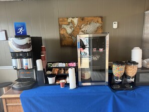 A coffee station with a coffee maker, cups, and a map on the wall. - Grant Hills Motel (Galena)