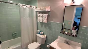 Un baño con ducha, inodoro, lavamanos y espejo.