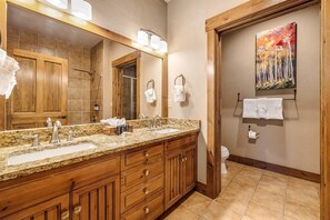 A bathroom with wooden cabinets, a granite countertop, a large mirror, and a painting on the wall. - 2 Bedroom Ski-in Condo at Mountain Thunder Lodge (Breckenridge)