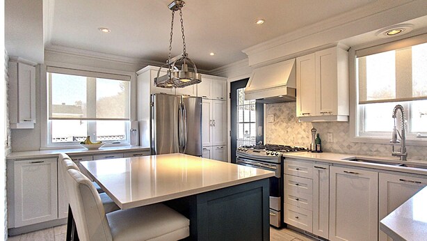 A modern kitchen with a large island, stainless steel appliances, and ample natural light.
