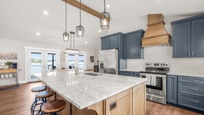 Une cuisine moderne dotée d’un grand îlot central, d’appareils électroménagers en acier inoxydable et de meubles de couleur bleue.