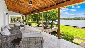 Un espace extérieur abrité, aménagé avec des meubles en osier et offrant une vue sur un lac.