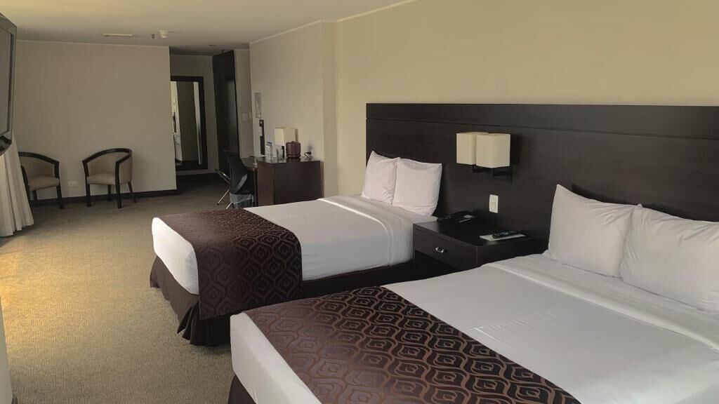 Ein Hotelzimmer mit zwei Betten, einem Schreibtisch, einem Stuhl und einem Fernseher.