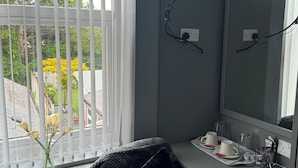 A modern room with a large window, a flat-screen TV, a mirror, and a small table with cups and a pitcher. - Waverley park house (Preston)