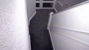 A narrow hallway with a carpeted floor and white walls. - Waverley park house (Preston)