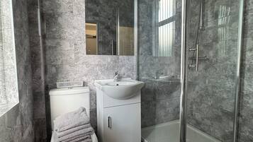 A modern bathroom with a toilet, sink, and glass-enclosed shower.