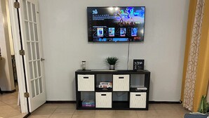A living room with a foosball table, a TV mounted on the wall, a sofa, and a cabinet with storage boxes. - Lawton/Fort Sill Home near Airport  (Lawton)