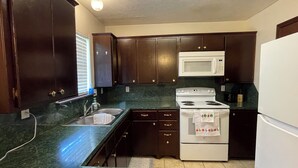 A kitchen with dark wooden cabinets, a white stove, and a white microwave. - Lawton/Fort Sill Home near Airport  (Lawton)