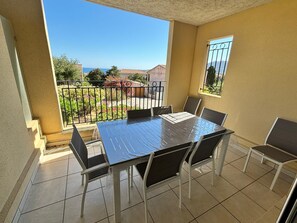 A balcony with a table and chairs, a view of the sea, and a railing.