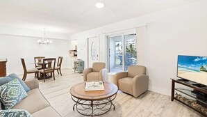 A modern living room with a sofa, a round coffee table, and a TV on a stand.