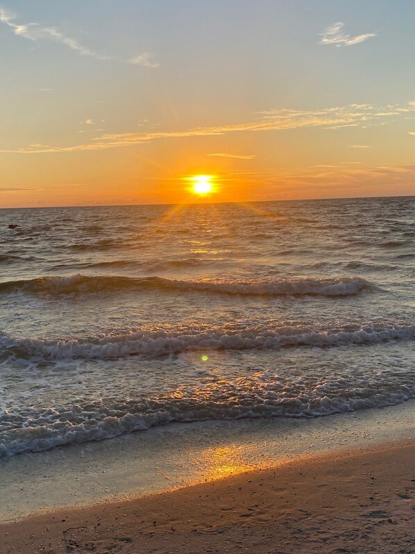 Una playa con olas y un atardecer.