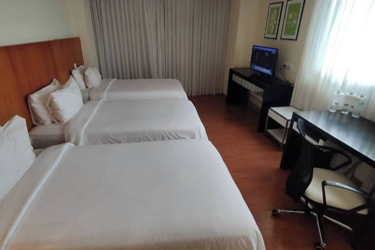Ein Hotelzimmer mit zwei Betten, einem Schreibtisch, einem Stuhl und einem Computer.