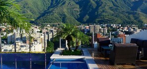A rooftop pool area with a view of a cityscape and mountains in the background. - Hotel Pestana Caracas Premium (Caracas)