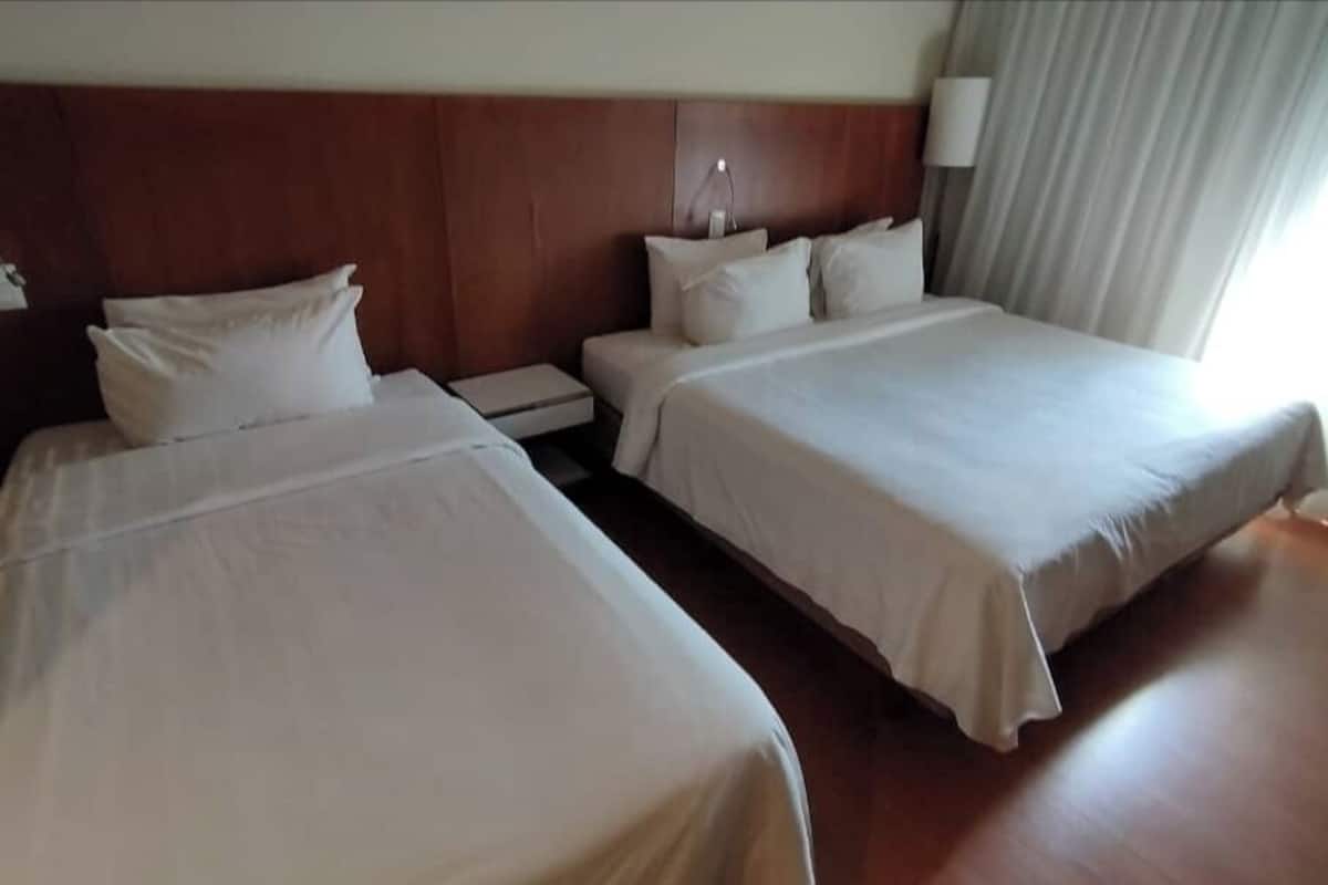 Ein Hotelzimmer mit zwei Betten, einem Holzkopfende, einem Nachttisch und einer Lampe.