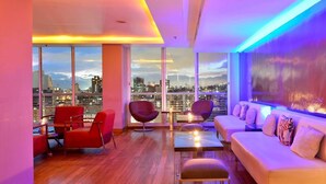 A modern living room with a city view, featuring a sofa, chairs, and a coffee table. - Hotel Pestana Caracas Premium (Caracas)
