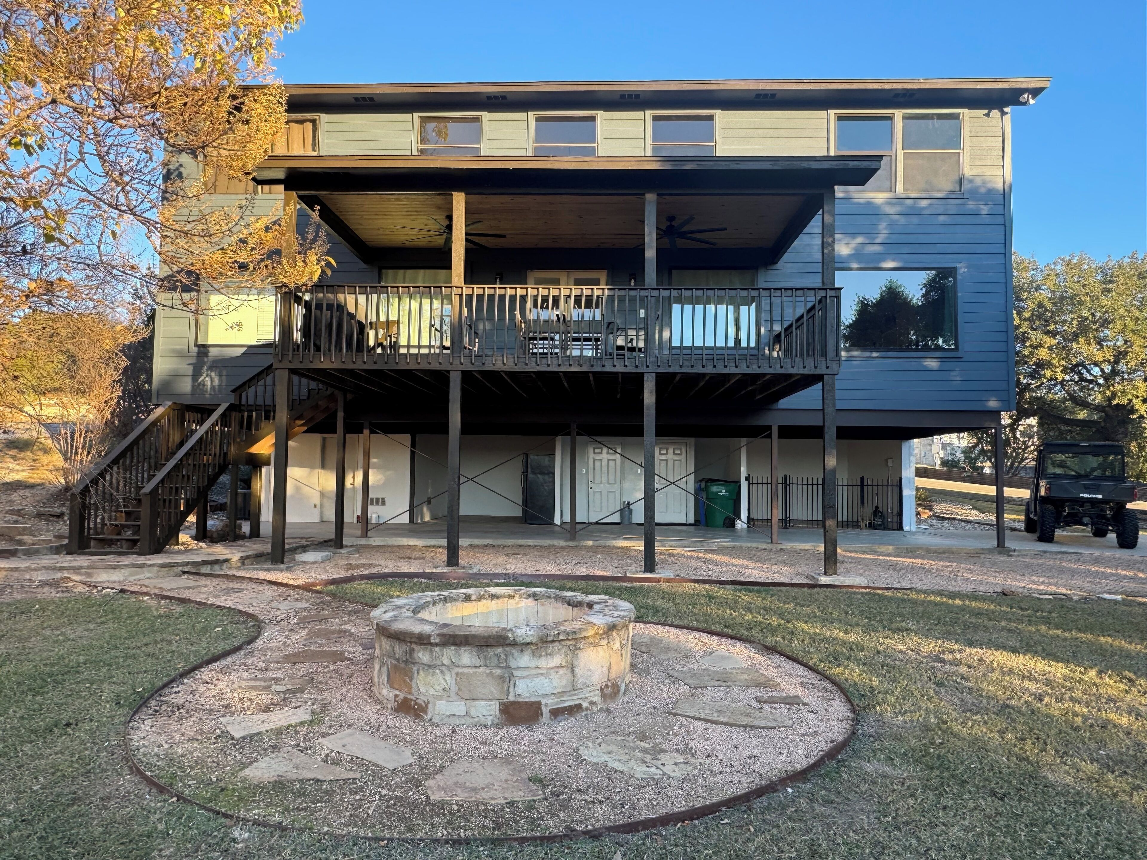 A two-story building with a covered patio area, a fire pit, and a vehicle parked outside.
