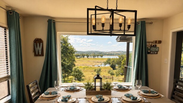 Comedor con mesa dispuesta para seis personas, vista a un lago y una araña.