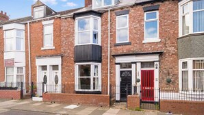 A row of terraced houses with distinct front doors, some with bay windows, and a clear blue sky.