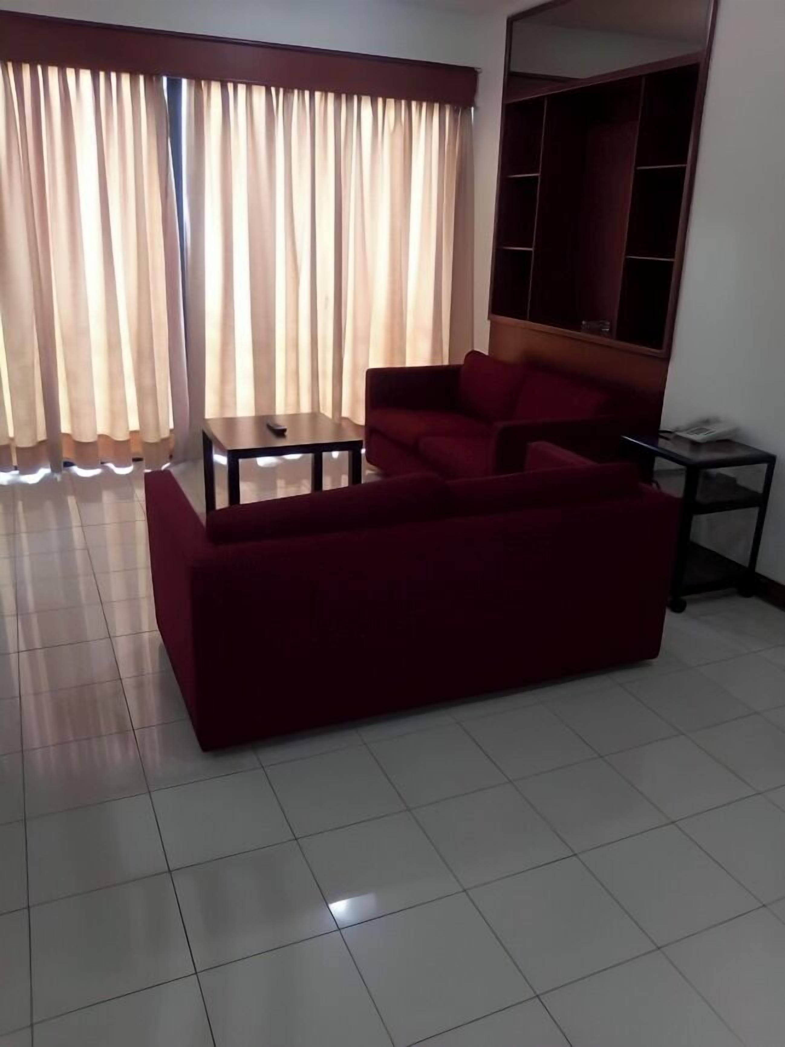 A living room with a red sofa, a small table, and a TV stand.