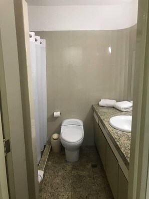 A small, compact bathroom with a toilet, sink, and shower curtain. - Hotel Cuarta Avenida (Caracas)