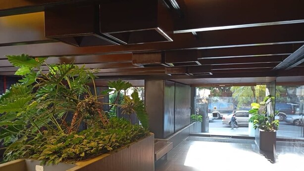A modern interior with a large planter with greenery, a glass door leading outside, and a tiled floor. - Hotel Cuarta Avenida (Caracas)