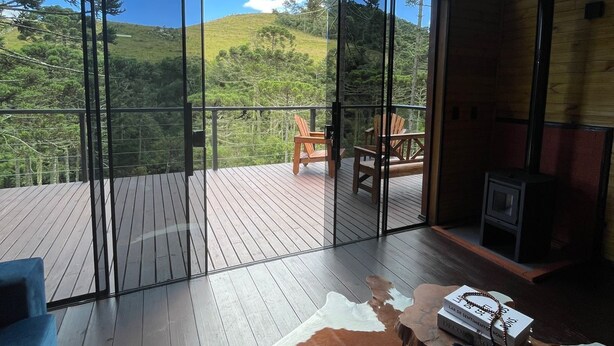 Una habitación amplia con una gran terraza de madera, un tapete de cuero y vistas a un paisaje montañoso.