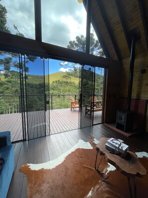 Una habitación amplia con una gran terraza de madera, un tapete de cuero y vistas a un paisaje montañoso.